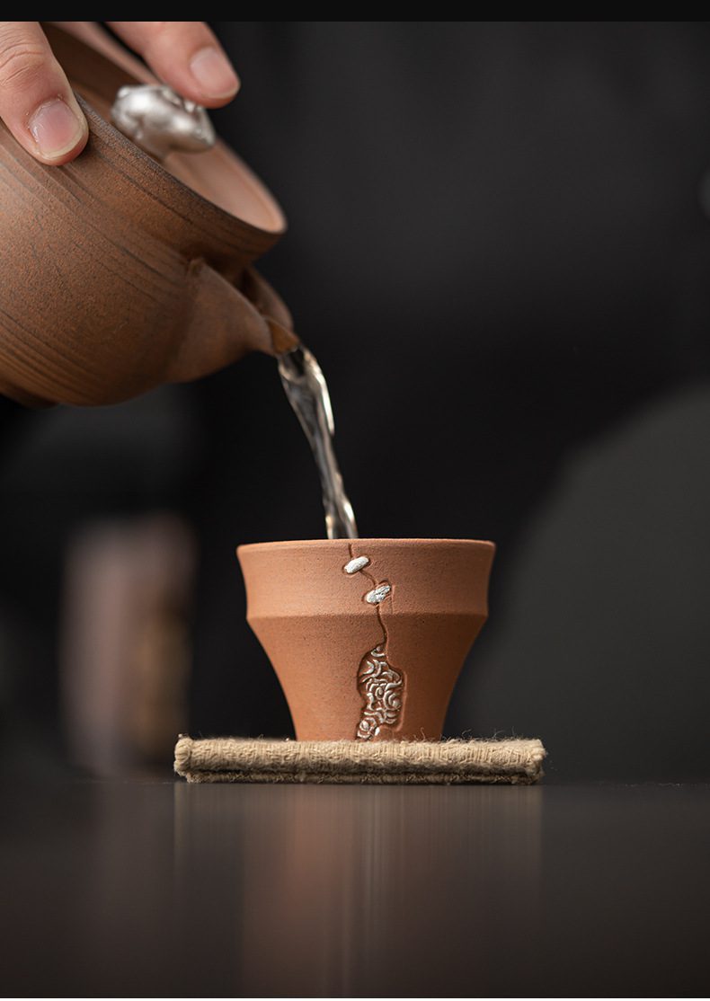 空寂老岩泥銅釘品茗杯，南山居手工粗陶茶杯，杯身點綴精緻銀飾修補工藝，壺中注茶展現古樸禪意美學。