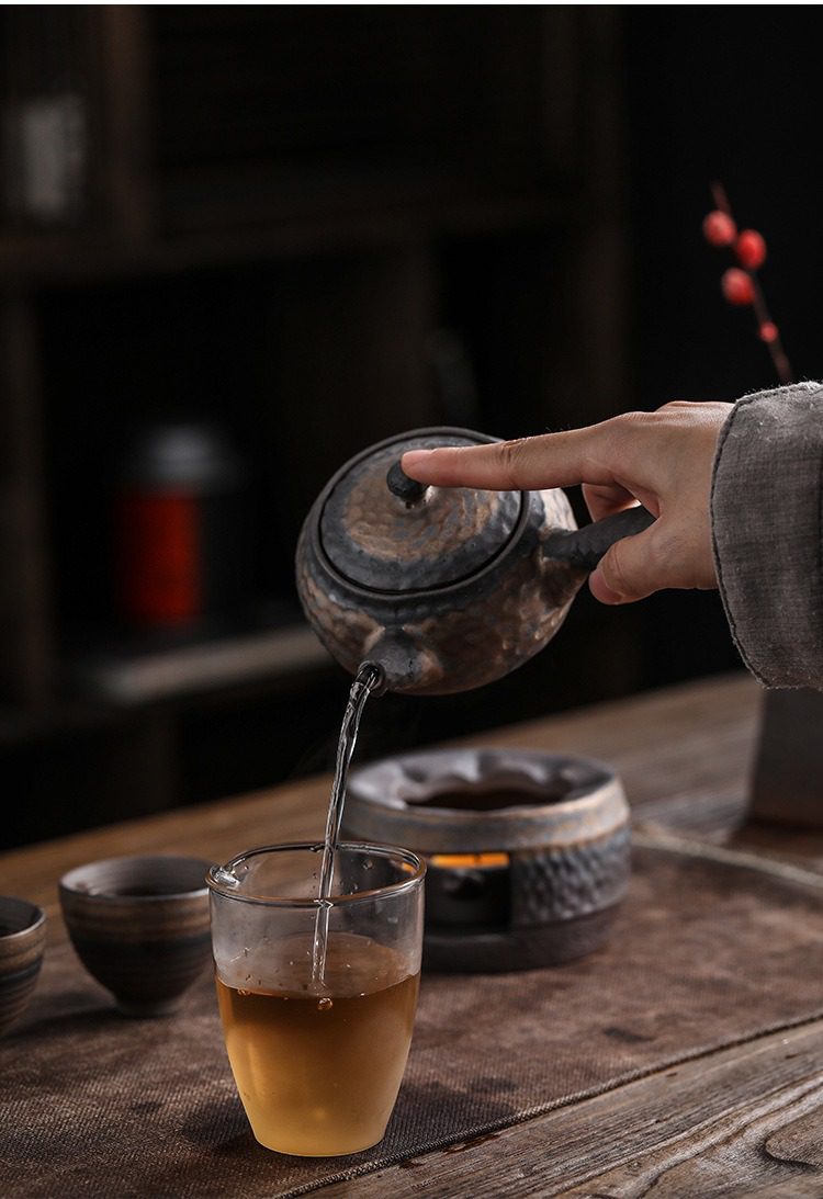 古早燒鎏金溫茶爐,南山居手工粗陶茶壺,壺身呈現古樸錘紋質感,注水線條流暢,展現深厚禪意品茗氛圍。