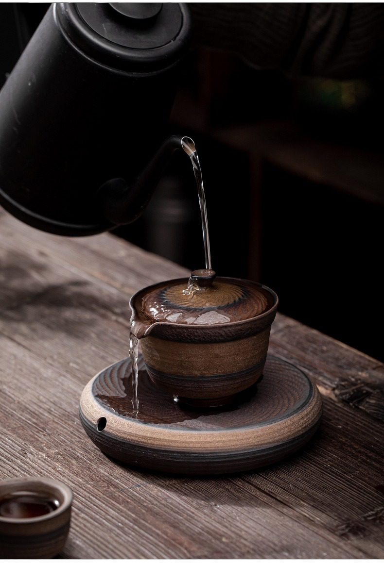 古早燒憨博手抓壺，南山居粗陶蓋碗沖泡茶湯，杯身紋理古樸自然，與圓形禪意茶盤相映成趣，展現極致品茗意境。