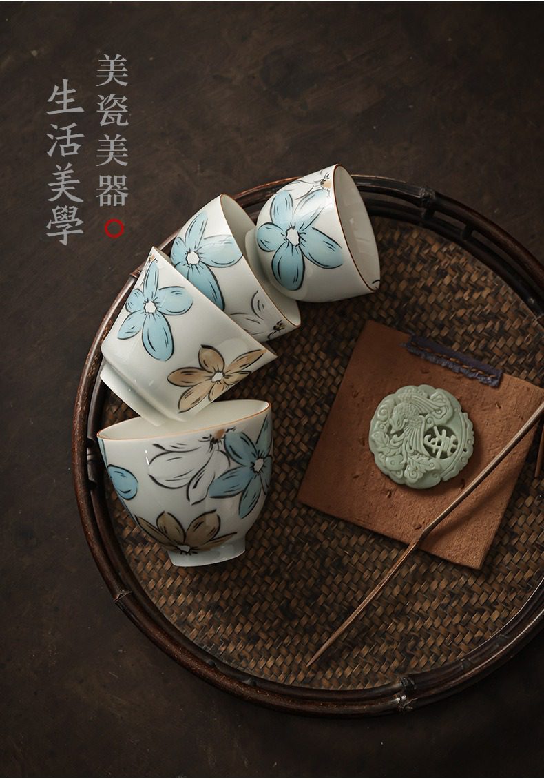 漫花品茗杯，南山居手繪花卉陶瓷茶杯組，杯身描繪清新藍白花紋，搭配竹編茶盤與精緻玉珮裝飾，展現典雅茶道美學。