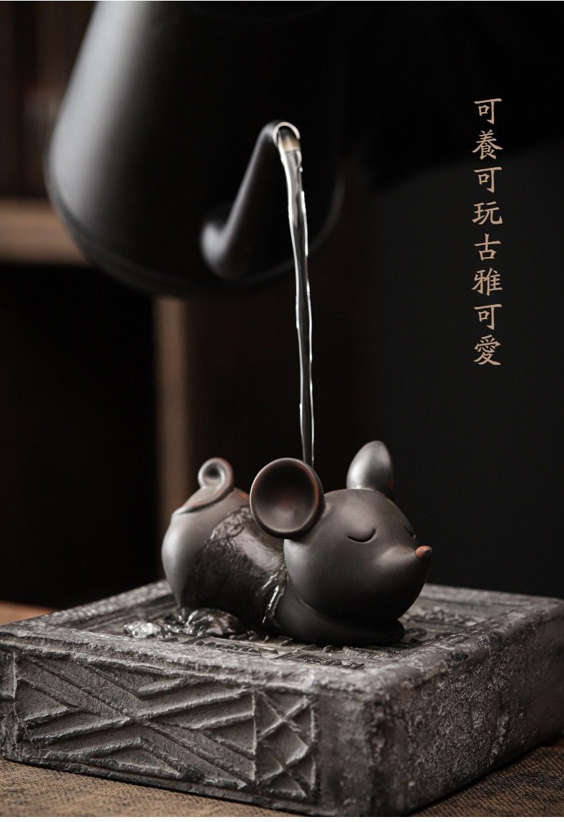 黑陶清溪過濾茶漏，南山居黑泥茶寵小老鼠，造型精緻靈動，正在接受沸水淋澆，為茶桌增添雅趣與生機。