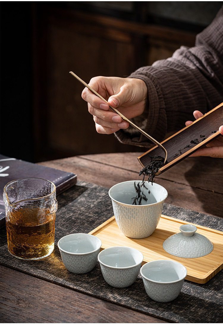 影青瓷溫馨快客杯，南山居手工青瓷編織紋蓋碗組，茶人正以竹製茶則撥茶入碗，質感溫潤優雅。