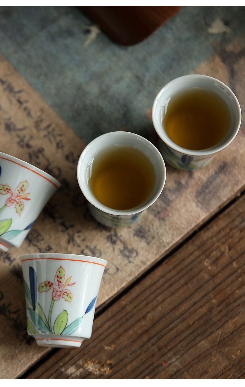 手繪鳶尾花品茗杯，南山居精緻手繪花卉瓷杯，釉面細膩溫潤，杯中琥珀茶湯映射出淡雅禪意，適合作為品茗鑑賞之器。