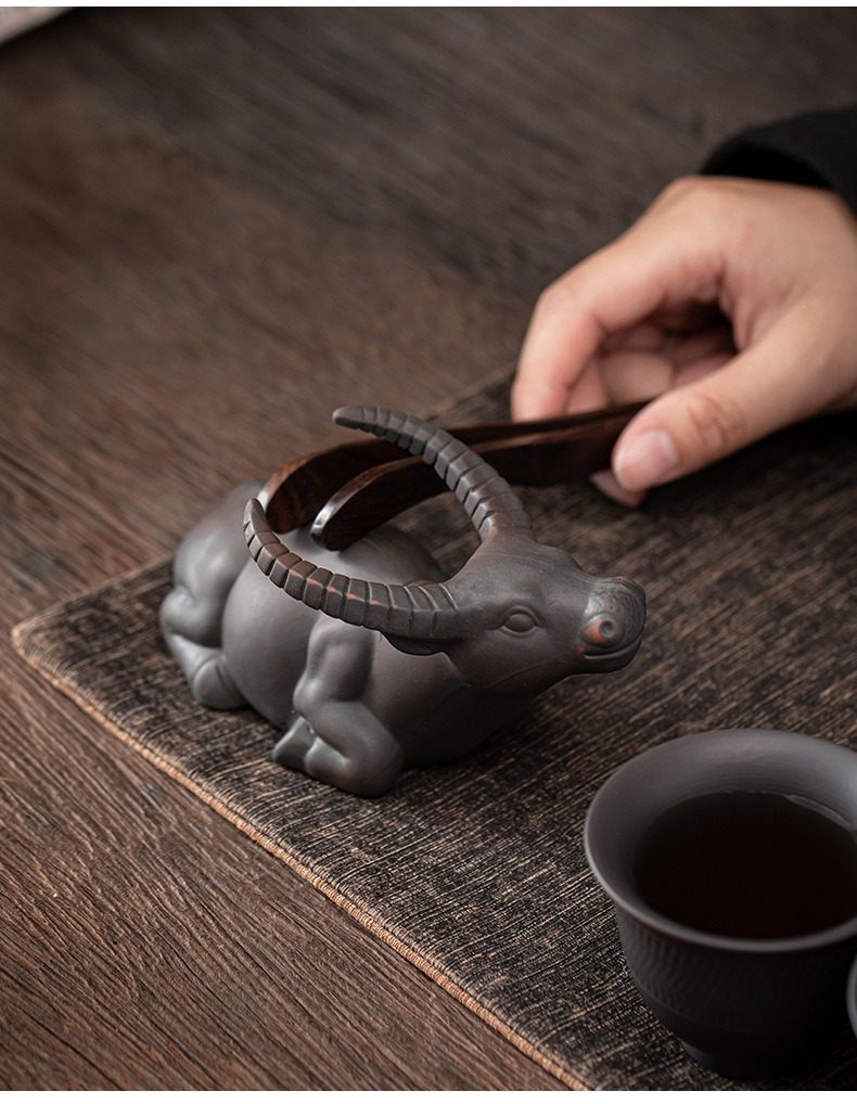 紫陶清溪自動茶具組，南山居精緻紫砂茶寵，生動臥牛造型雕刻細膩，搭配深色木質茶夾，展現雅緻茶道美學。