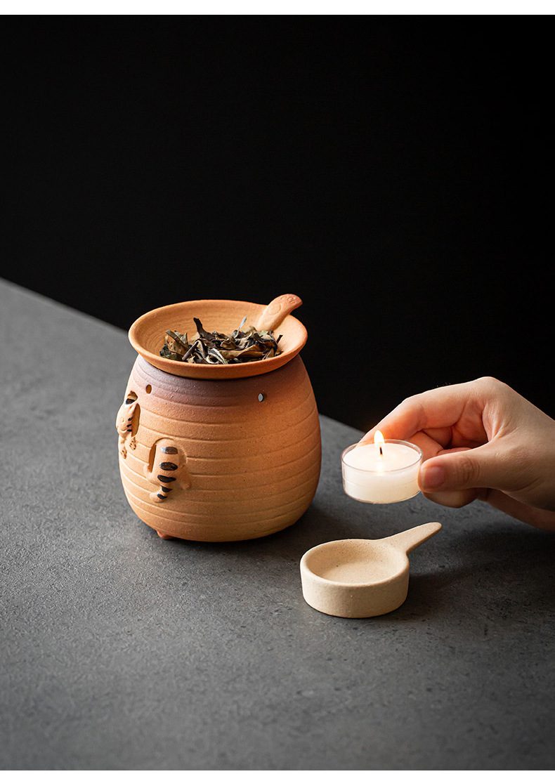 古早燒小貓烤茶爐，南山居手工陶製茶葉焙香爐，以虎紋浮雕裝飾，搭配燭火加熱，展現溫潤質樸的品茗氛圍。