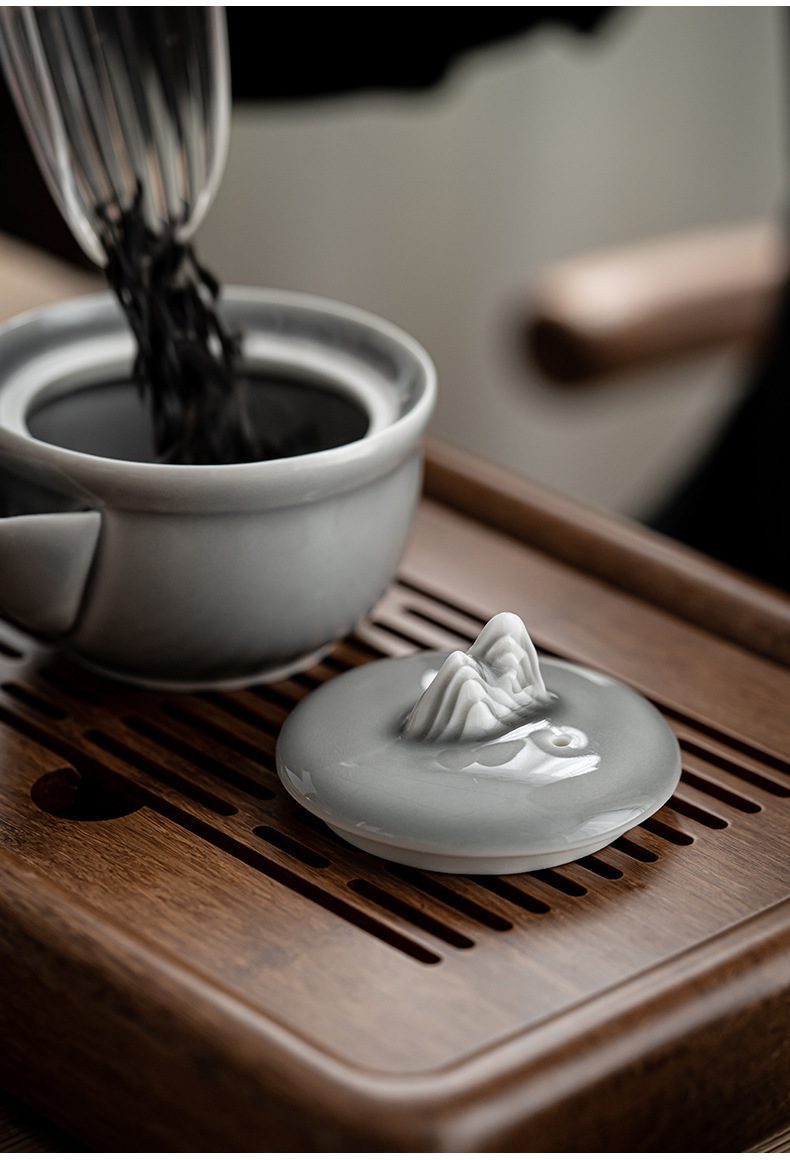 冰灰釉手抓壺，南山居禪意山水蓋碗，壺蓋飾有精緻立體山形鈕，釉色溫潤如玉，為茶道空間增添雅致氣息。