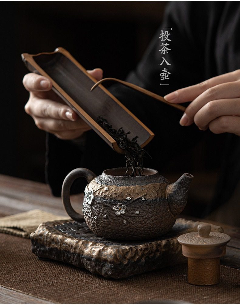 古早燒鎏金暗香正把壺，南山居手工粗陶茶壺，壺身雕刻精緻梅花圖案，茶人正以竹製茶則進行投茶儀式，展現古樸雅致的茶文化。