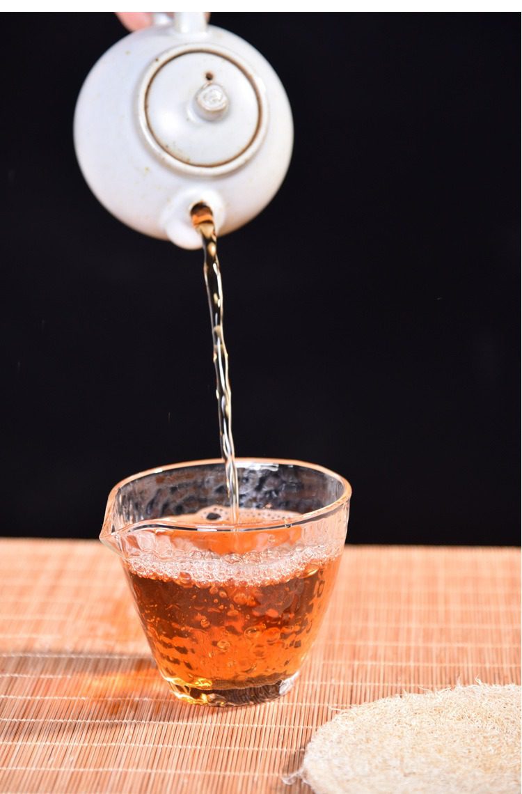 玻璃錘目紋公道杯，南山居白色陶瓷手沖壺將琥珀色茶湯注入晶瑩玻璃公道杯，展現優雅茶道。