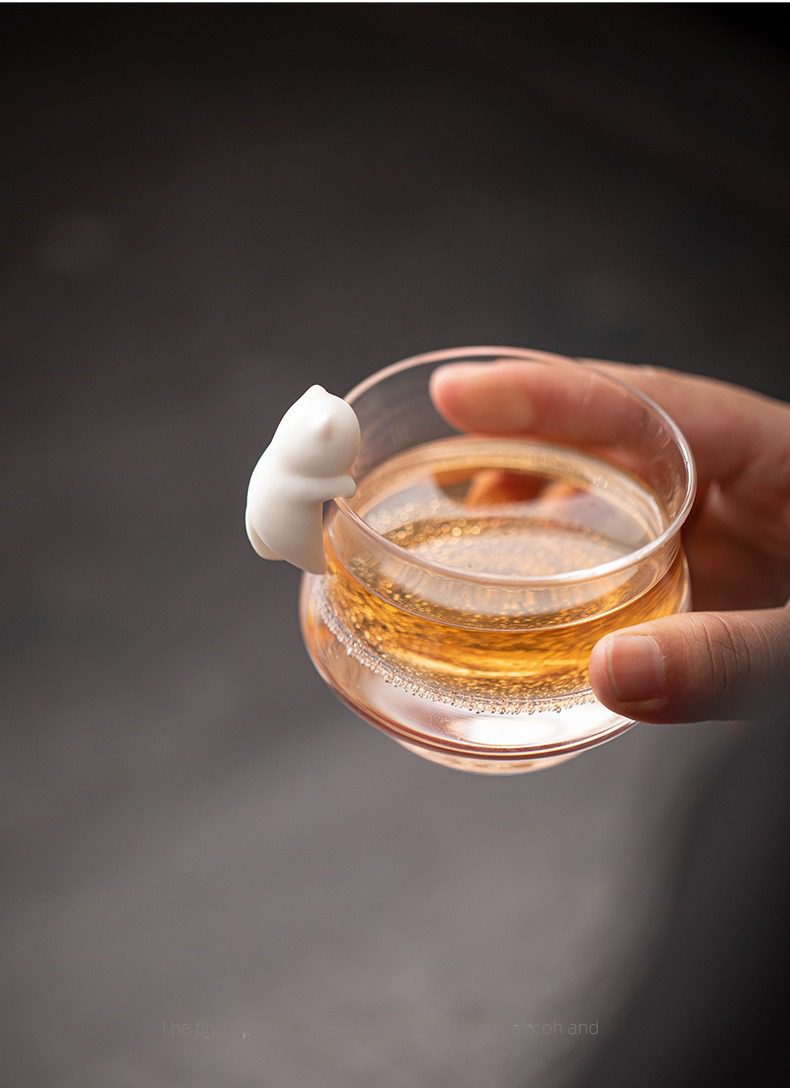 白瓷貓咪掛件茶寵，南山居手工玻璃茶杯，杯緣設有可愛陶瓷貓咪裝飾，晶瑩剔透，展現茶湯澄澈色澤。