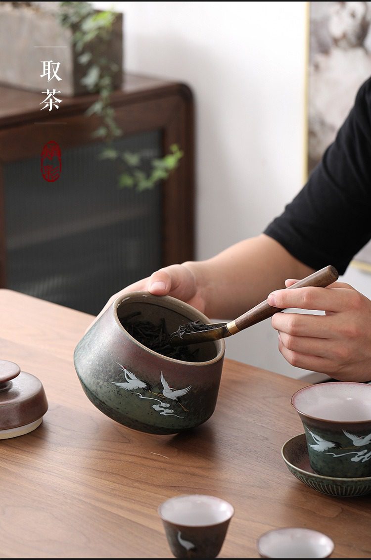 窯變煥彩瑞鶴呈祥茶葉罐，南山居手繪仙鶴粗陶茶倉，漸變釉色雅致，搭配木柄茶勺輕取條索茶葉，展現茶道日常。