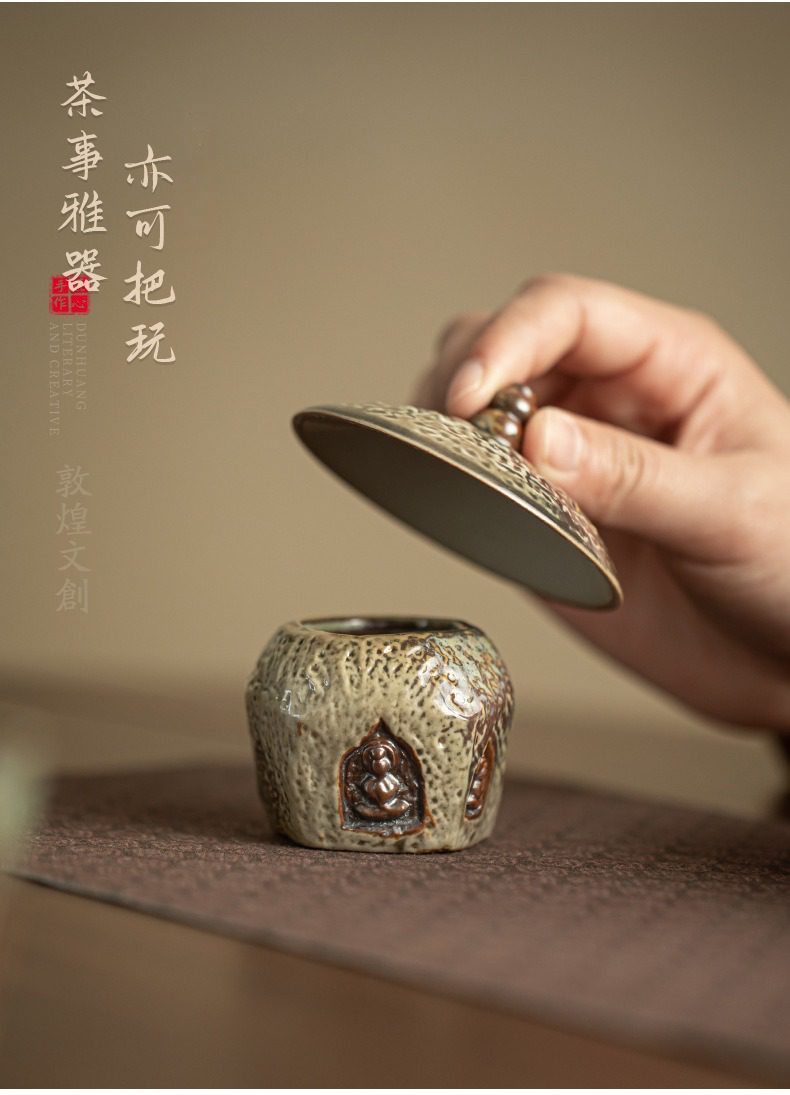 敦煌印象圓隱蓋置，南山居敦煌文創系列茶倉，粗陶質感，壺身精雕佛像，兼具實用與觀賞價值，適合作為茶席擺件。