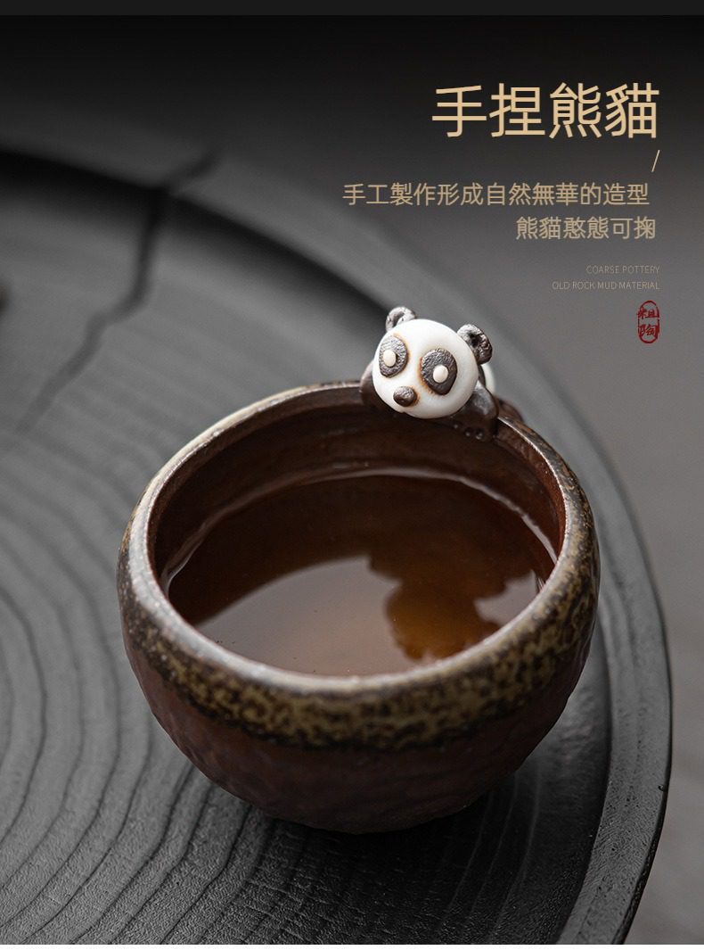 古早燒粗陶熊貓品茗杯，南山居手捏熊貓粗陶茶杯，憨態可掬的熊貓點綴杯緣，泥質古樸溫潤，盛滿茶湯。