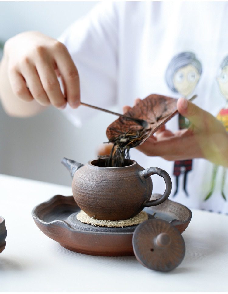 古早燒螺紋茶壺，南山居手工粗陶茶壺搭配天然葉形茶則，將烏龍茶葉緩緩置入壺中，展現茶道靜謐之美。