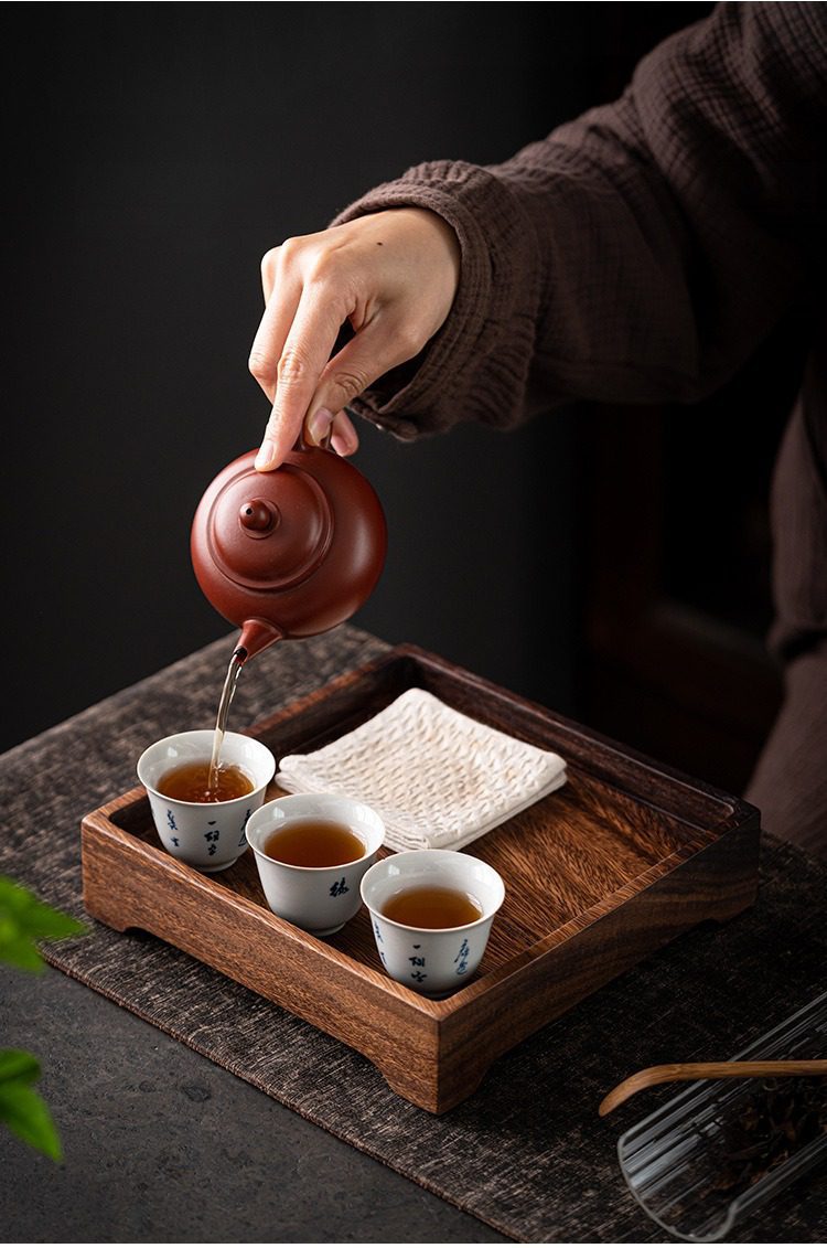 胡桃木方愉乾泡茶盤，南山居手工朱泥紫砂壺，壺身圓潤流暢，搭配青花茶杯，展現優雅泡茶。