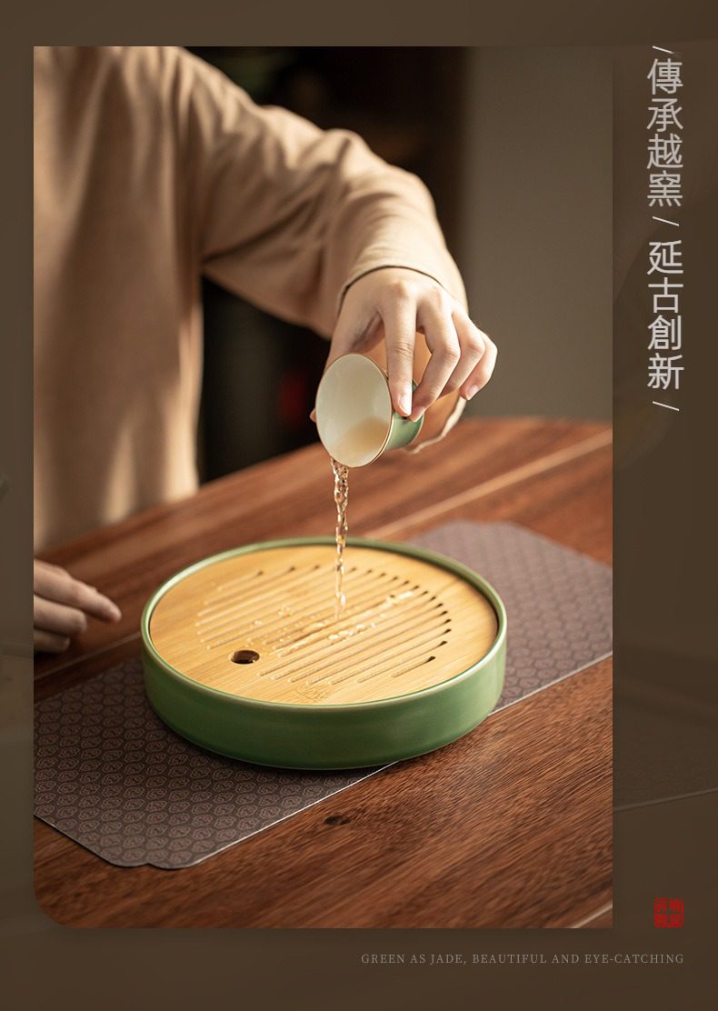 青璃釉圓然乾泡茶盤，南山居墨綠陶瓷竹製茶盤，設計簡約具禪意，茶師手持茶杯於茶席上注水，彰顯優雅品茗
