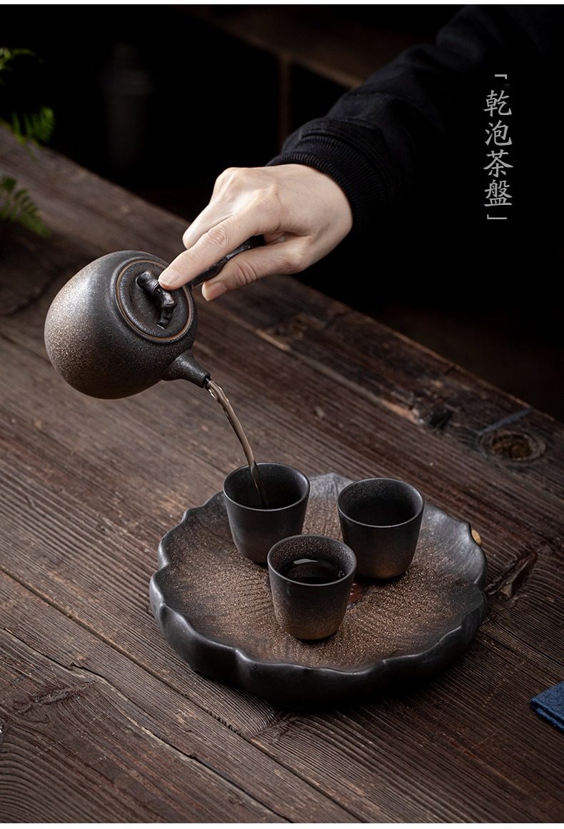 窯變青野壺承，南山居手作粗陶側把壺，正將茶湯注入荷葉形乾泡茶盤上的品茗杯，展現侘寂茶席美學。