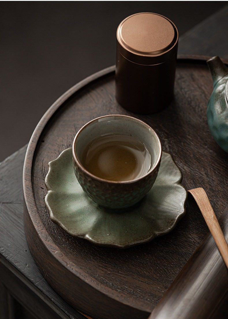 窯變青野杯墊，南山居手工粗陶茶杯與葉形茶托，杯中茶湯澄澈，釉色樸實自然，呈現獨特茶道美學。