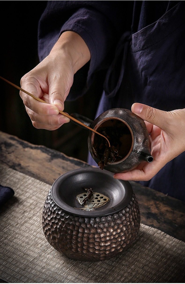 窯變青野蓮蓬建水，南山居粗陶橫把壺與蜂巢紋茶渣缸，茶師用竹茶勺輕撥茶葉，展現傳統泡茶之美。
