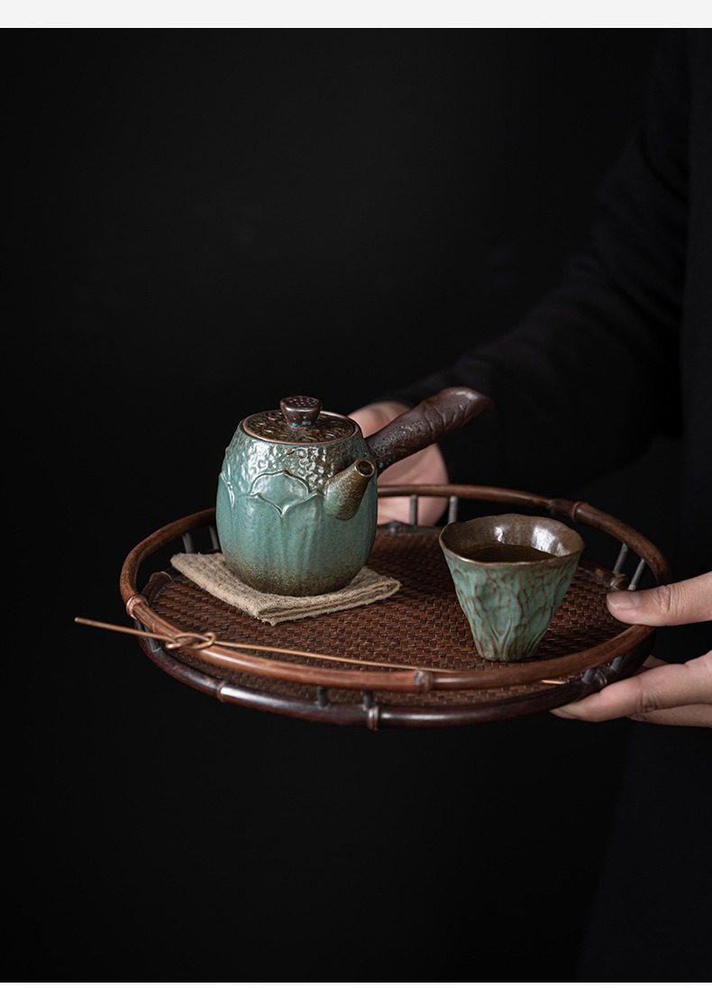 窯變青野蓮香側把壺，南山居手工青瓷側把壺與茶杯組，釉色溫潤青翠，壺身浮雕蓮花紋路，搭配竹編茶盤，盡顯禪意茶席美學。
