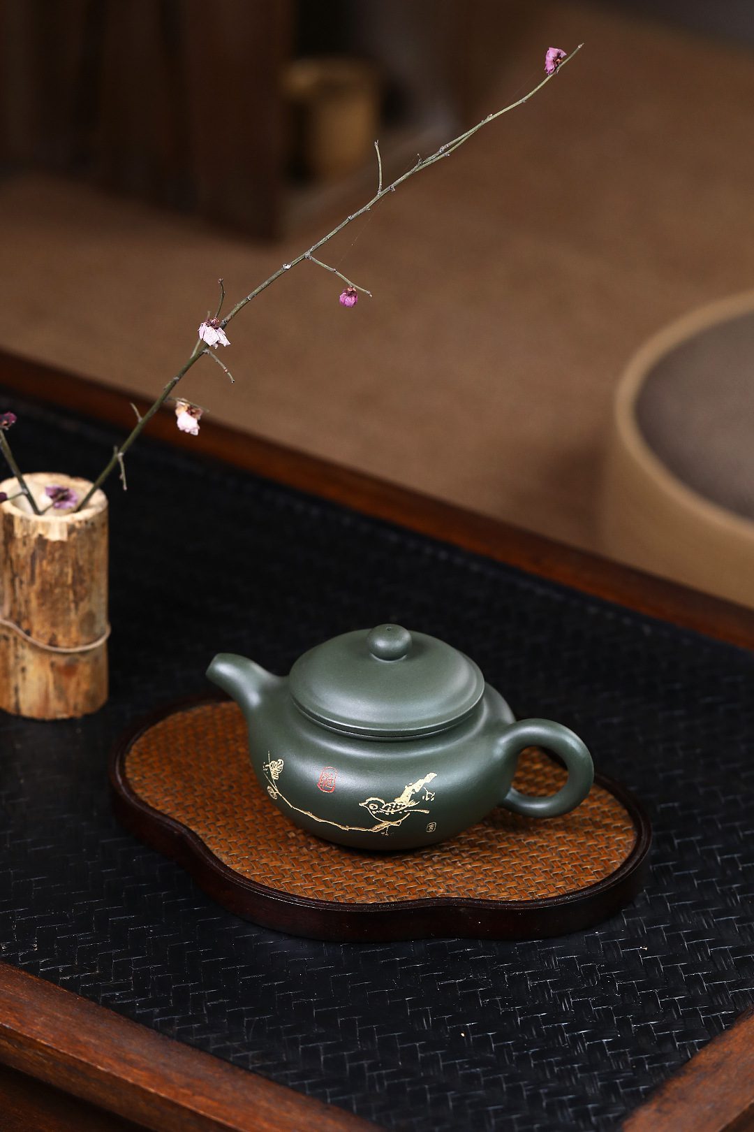 宜興紫砂壺原礦綠泥鳥趣仿古茶壺(250ml)，南山居墨綠泥紫砂壺，壺身圓潤，表面手繪精緻金色花鳥圖案，搭配竹編茶盤，彰顯雅致茶道。