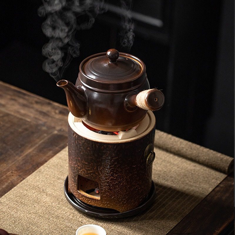 漸變炭火溫茶爐，南山居古樸陶製側把煮水壺置於炭爐上，壺嘴蒸氣氤氳，展現傳統煮水茶具的雅緻與實用性。