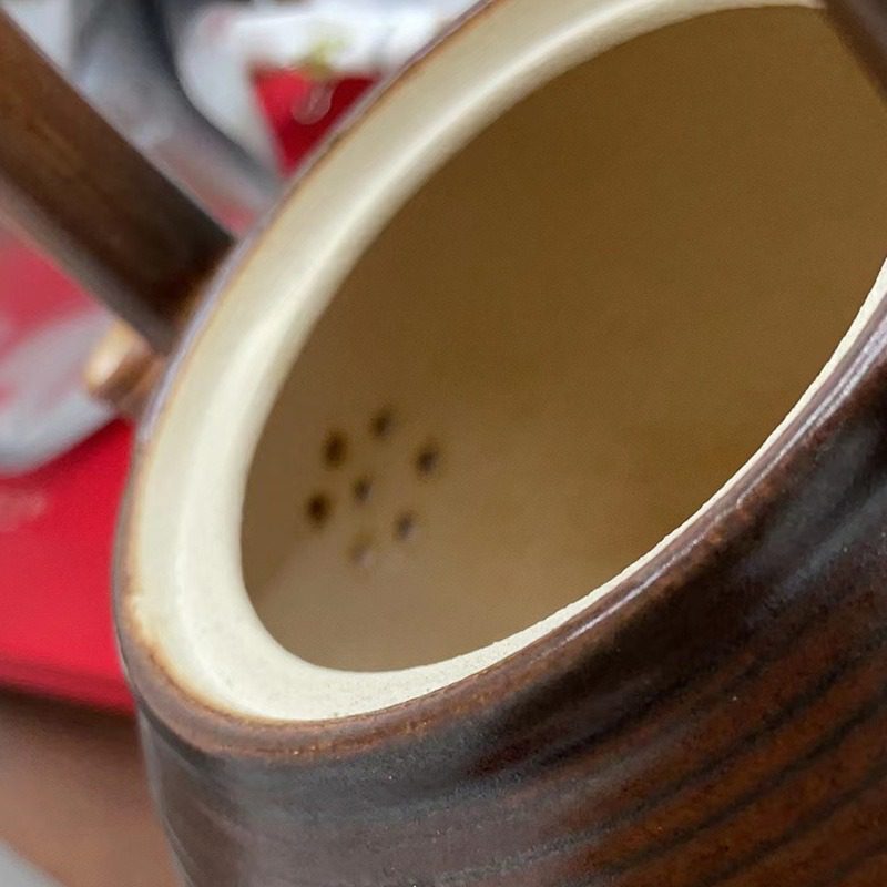 漸變炭火溫茶爐，南山居陶製提梁茶壺，深棕色壺身具手拉胚紋理，壺內設梅花形濾孔，內部淺米色。