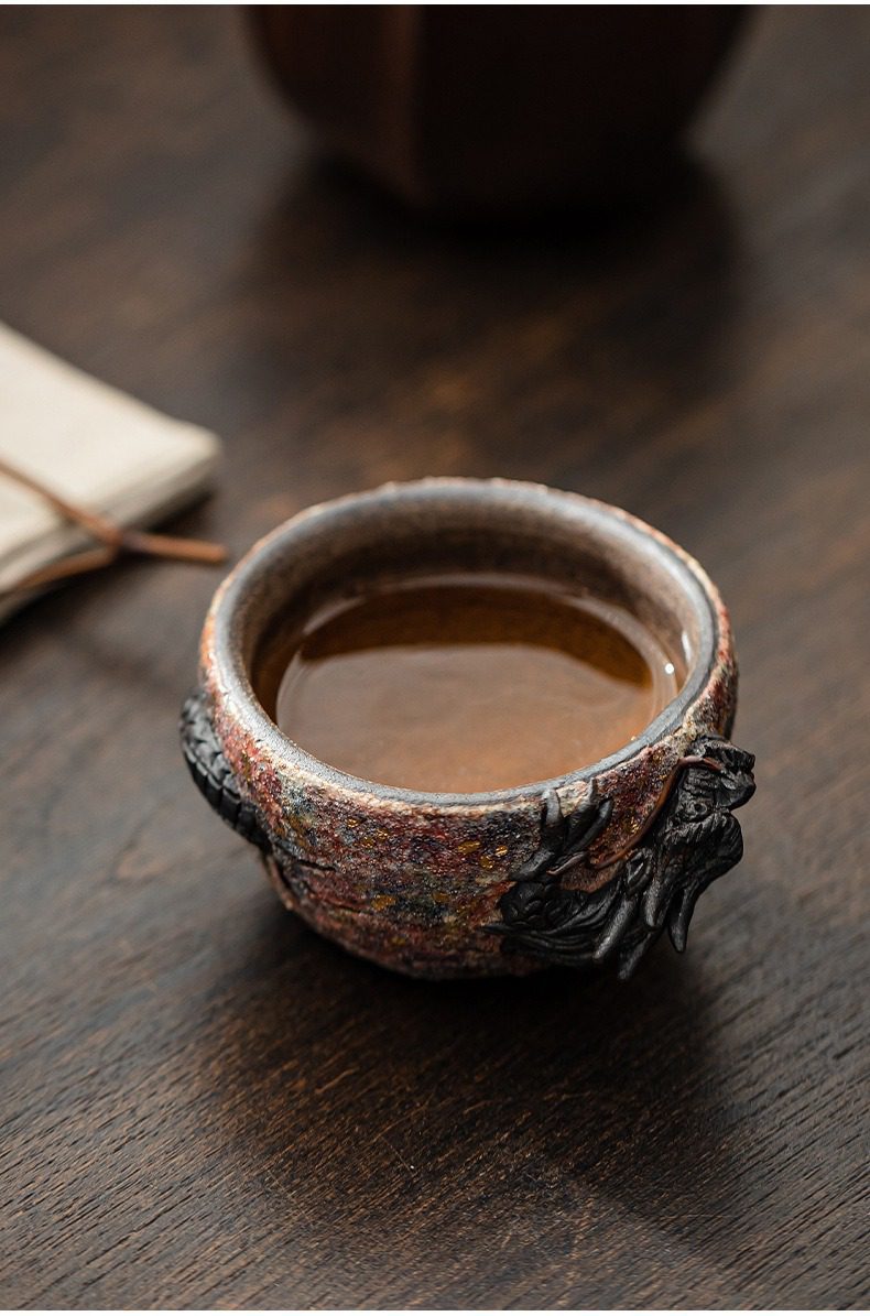 岩礦主人杯，南山居手工柴燒龍紋品茗杯，杯身肌理粗獷，浮雕龍首設計獨特，盛裝琥珀色茶湯。