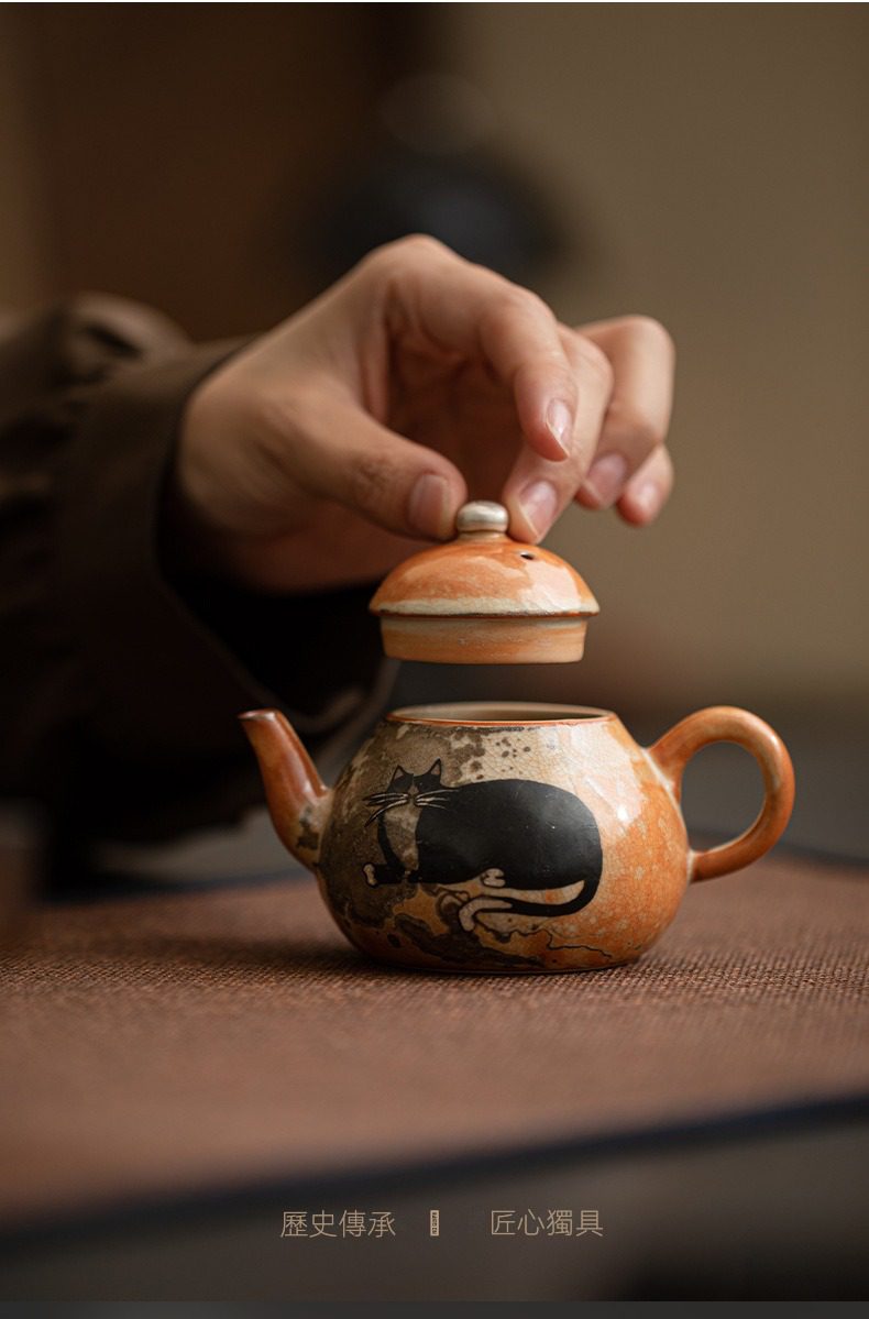 日式志野貓柴燒茶壺，南山居手繪貓咪陶壺，壺身橘棕色釉彩溫潤，黑色貓咪圖案活潑生動，精緻茶具。