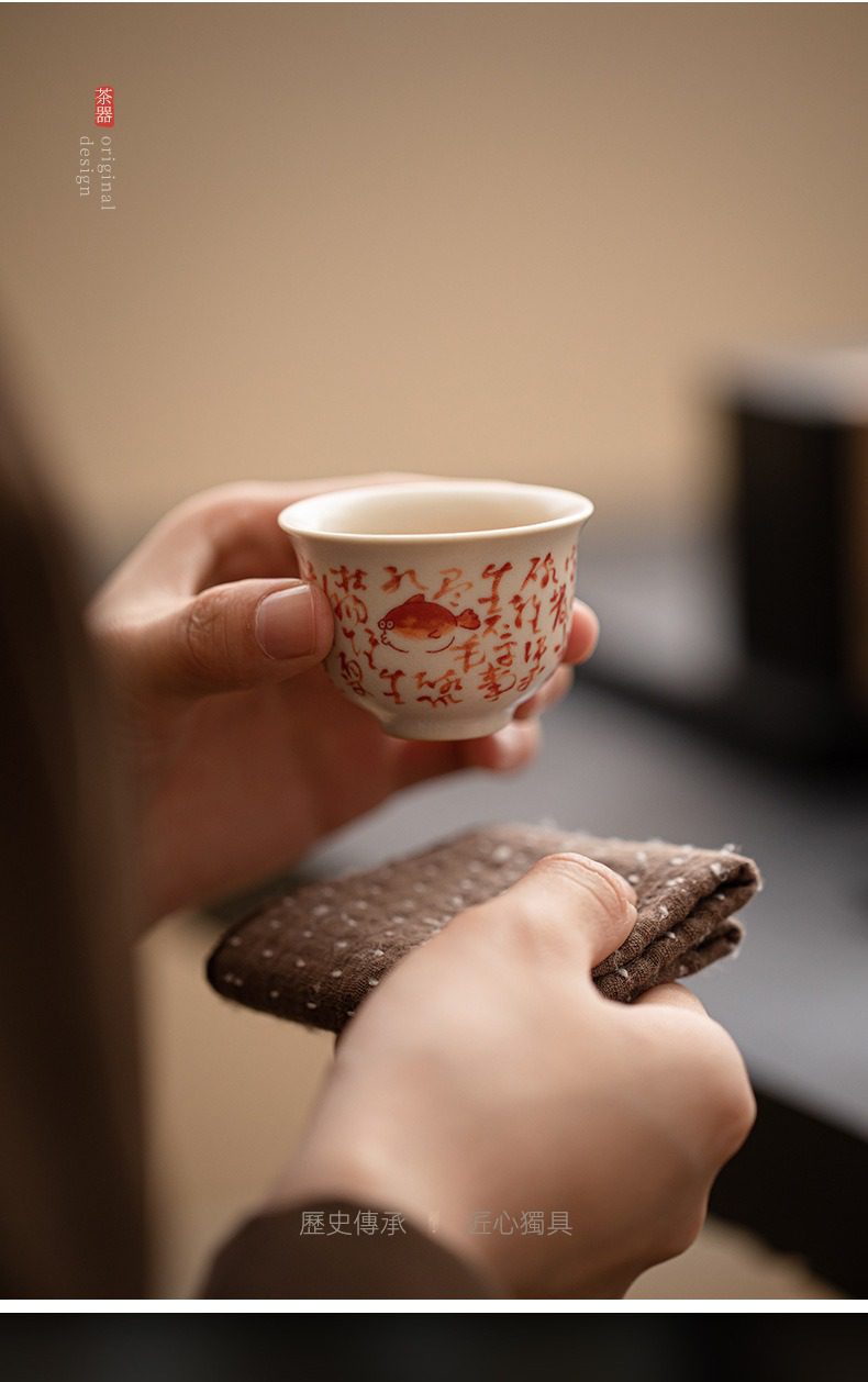 百圾碎蘇打釉品茗杯，南山居手繪魚紋陶瓷茶杯，杯身潔白溫潤，飾有吉祥魚圖與書法字，展現精緻功夫茶具之美。