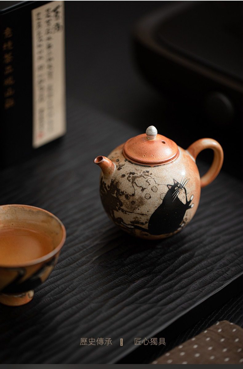 日式志野貓柴燒茶壺，南山居手繪貓咪陶壺，壺身圓潤，泥色古樸，黑貓圖案生動可愛，為茶席增添雅趣。
