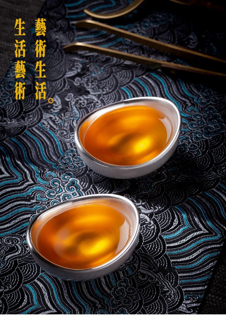 金銀元寶品茗杯，南山居手工純銀元寶茶杯，盛滿金黃茶湯，器型優雅，盡顯茶道之美。