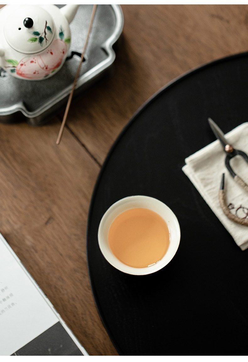 粉引 - 手繪壽桃品茗杯，南山居白色陶瓷品茗杯，內盛溫潤茶湯，搭配手繪花卉茶壺與茶盤，展現優雅茶道美學。