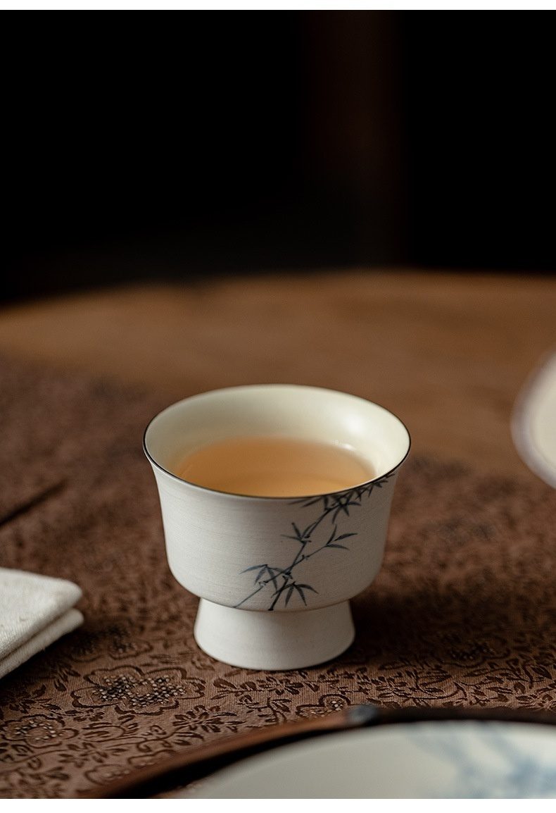 粉引白 - 手繪墨竹品茗杯，南山居手繪竹韻高足陶瓷茶杯，杯身潔白細膩溫潤，盛裝琥珀色茶湯，展現茶道美學。