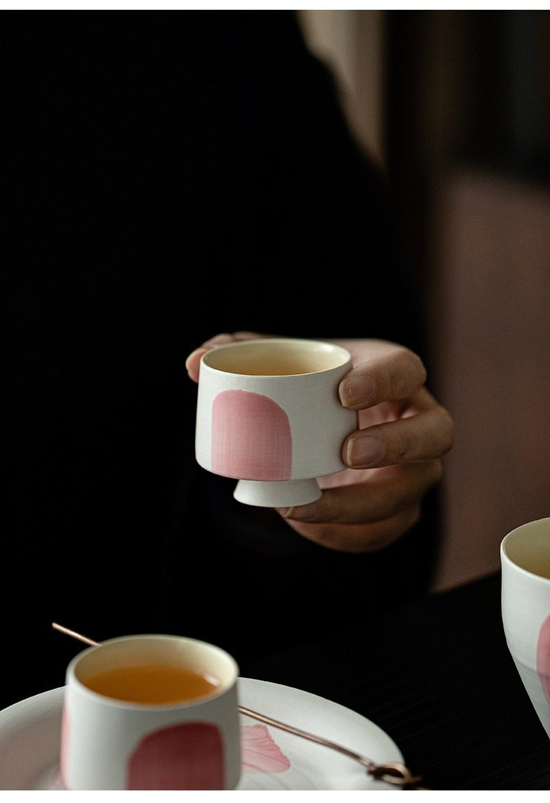 粉引白 - 水抹粉品茗杯，南山居藝術感粉色弧形手繪陶瓷品茗杯，由手輕輕托起，杯身簡約雅致，茶湯色澤溫潤，展現手工茶具之美。
