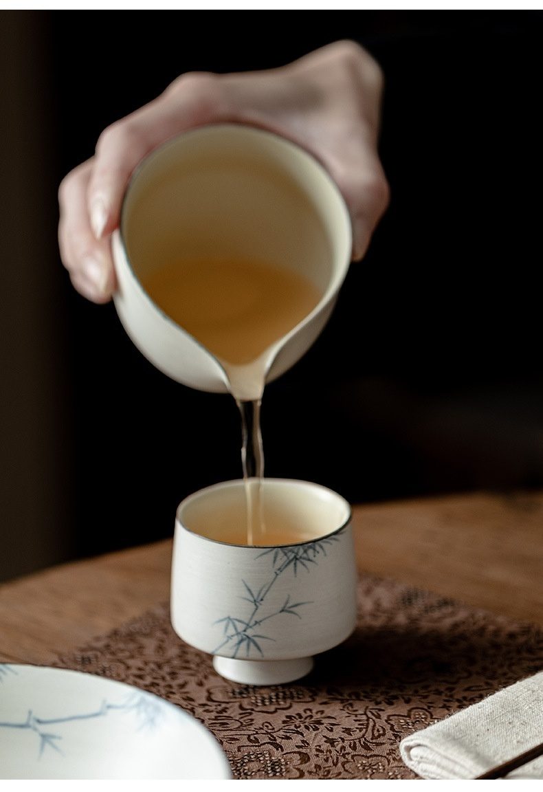 粉引白 - 手繪墨竹品茗杯，南山居手繪竹青陶瓷公道杯向茶杯傾注琥珀茶湯，展現茶席優雅。