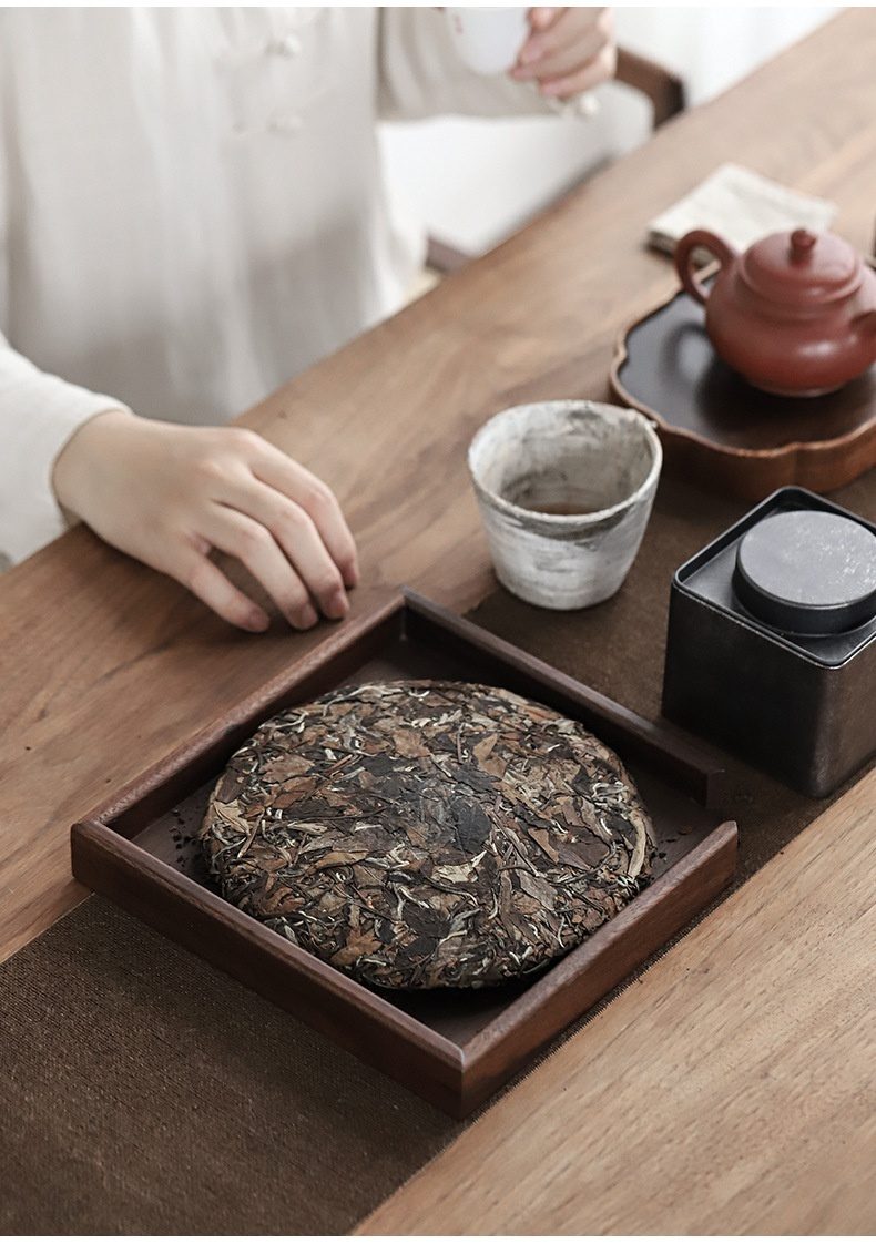 胡桃木普洱茶餅分茶盤，南山居陳年白茶餅，色澤古樸，茶葉條索清晰，置於實木茶盤上，營造靜謐品茗氛圍。