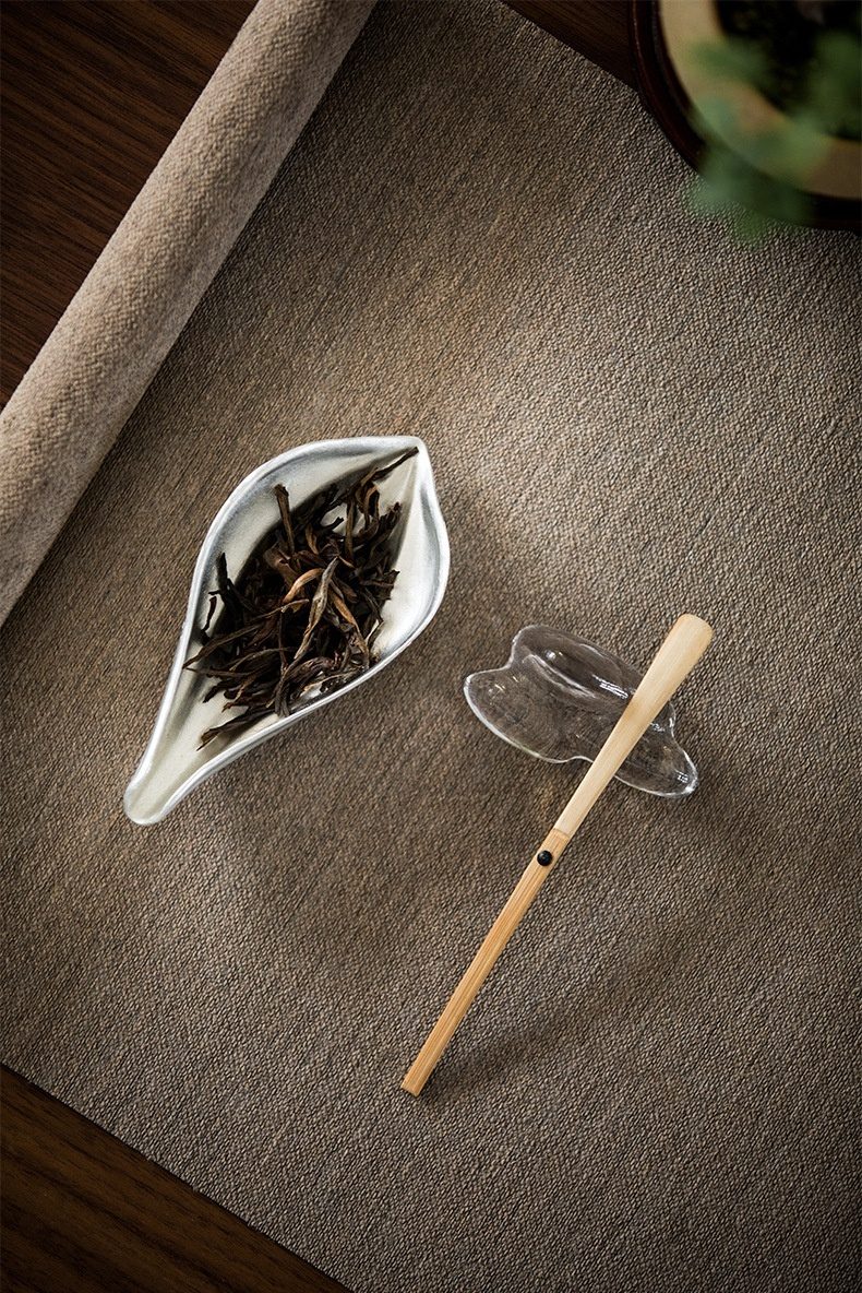 禪意手工錫蓮瓣茶則，南山居葉形茶則盛放烏龍茶葉，搭配竹製茶匙與雅致玻璃茶匙架，展現精緻茶具美學。