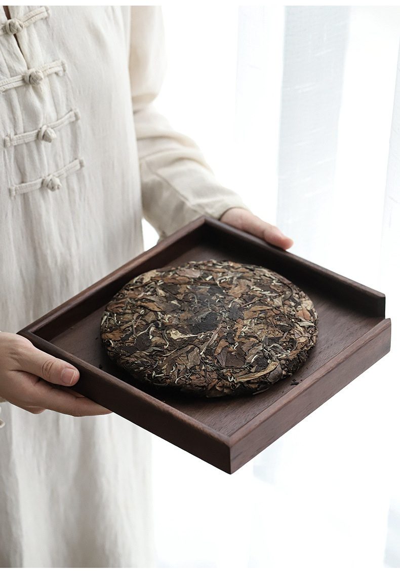 胡桃木普洱茶餅分茶盤，南山居高品質白茶餅，茶葉壓制圓潤飽滿，呈現銀白與墨綠交織之美，置於深色木托盤上，彰顯茶道雅趣。