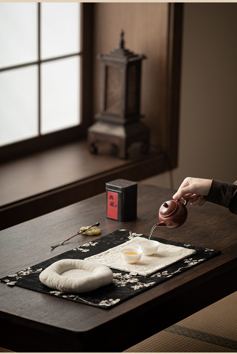 梅花刺繡織錦茶席桌巾壺承，南山居朱泥紫砂壺正手沖沏茶，壺身圓潤光澤，搭配精緻茶杯與茶席，展現優雅品茗時光。