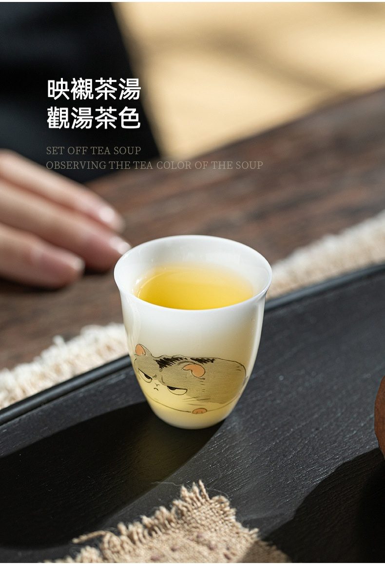 白皙玉泥十二生肖品茗杯，南山居手繪貓咪陶瓷品茗杯，杯中盛裝金黃茶湯，可愛貓咪圖案增添茶趣。