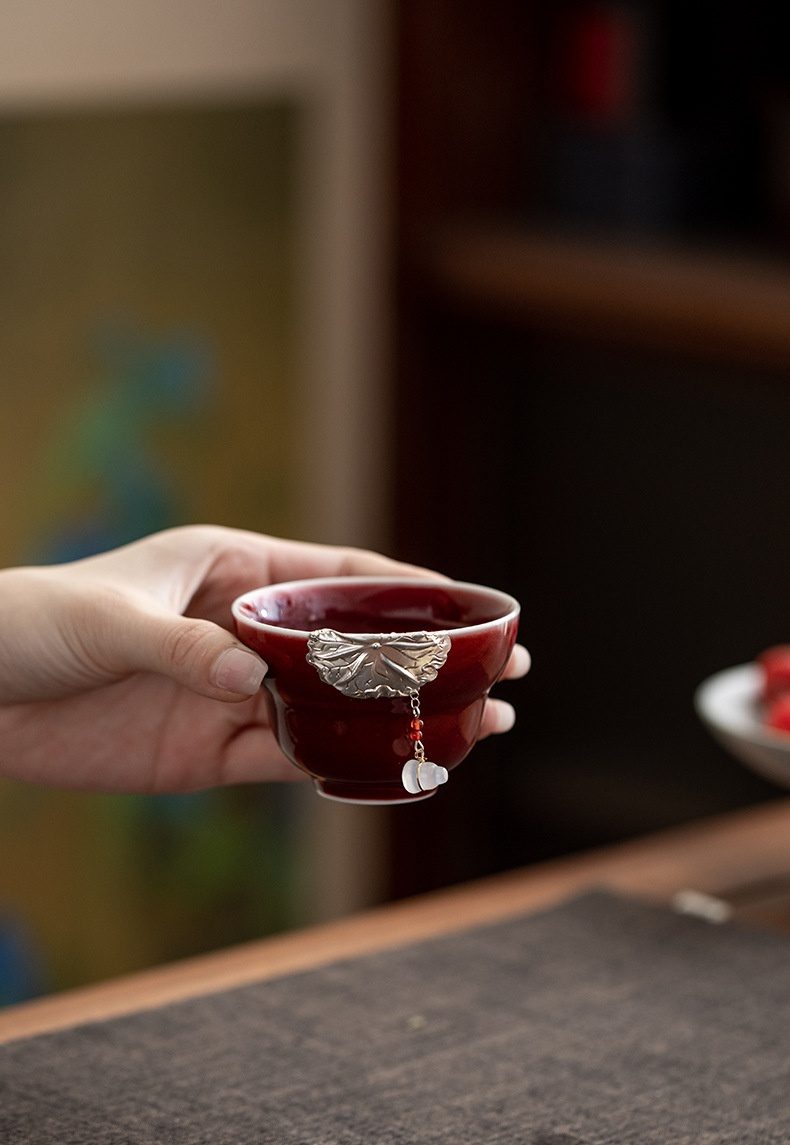 郎紅鑲銀蝴蝶荷韻品茗杯，南山居霽紅釉品茗杯，杯身緋紅溫潤，飾以精緻銀葉與白玉葫蘆吊墜，獨具禪意美學。
