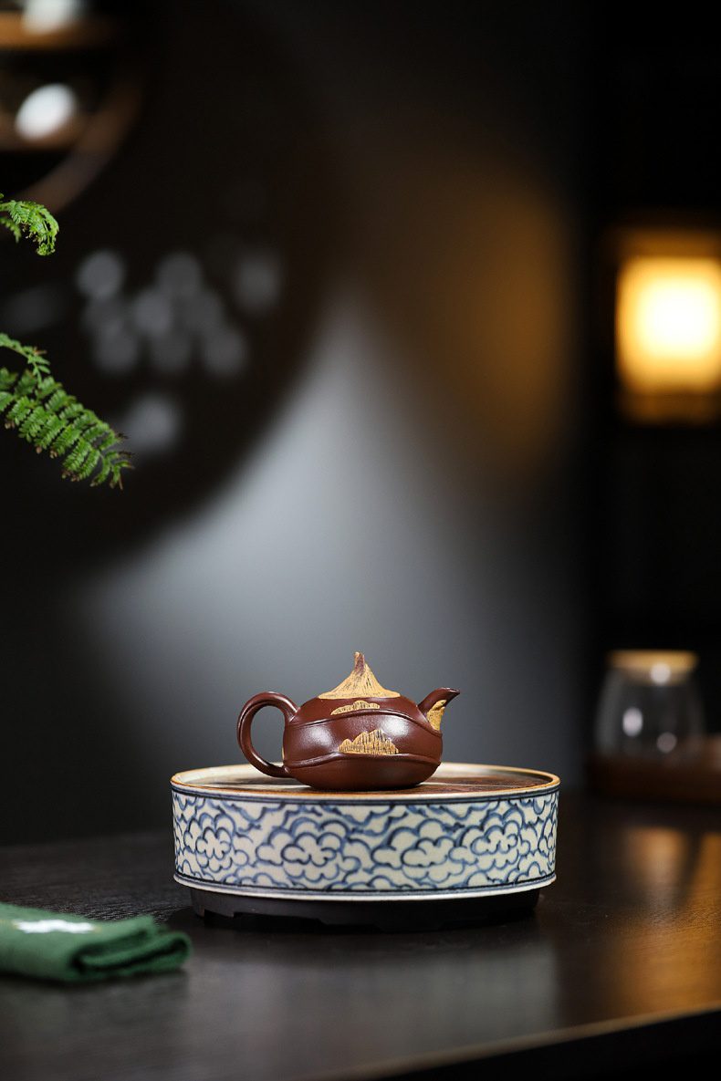 宜興紫砂壺原礦紫泥荸薺仿生壺(100ml)，南山居手工紫砂壺，深棕紅色泥料，壺身與尖頂壺蓋飾有金色山水紋，置於青花雲紋茶承。