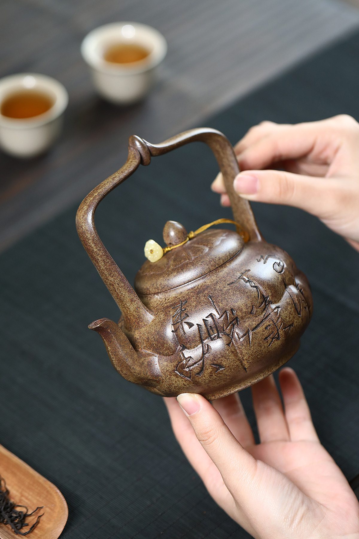 宜興紫砂壺原礦沉香泥筋紋焚蓮提梁壺(420ml),南山居手工紫砂提樑壺,壺身圓潤飽滿刻繪細膩,泥色古樸溫潤,展現獨特茶器美學。
