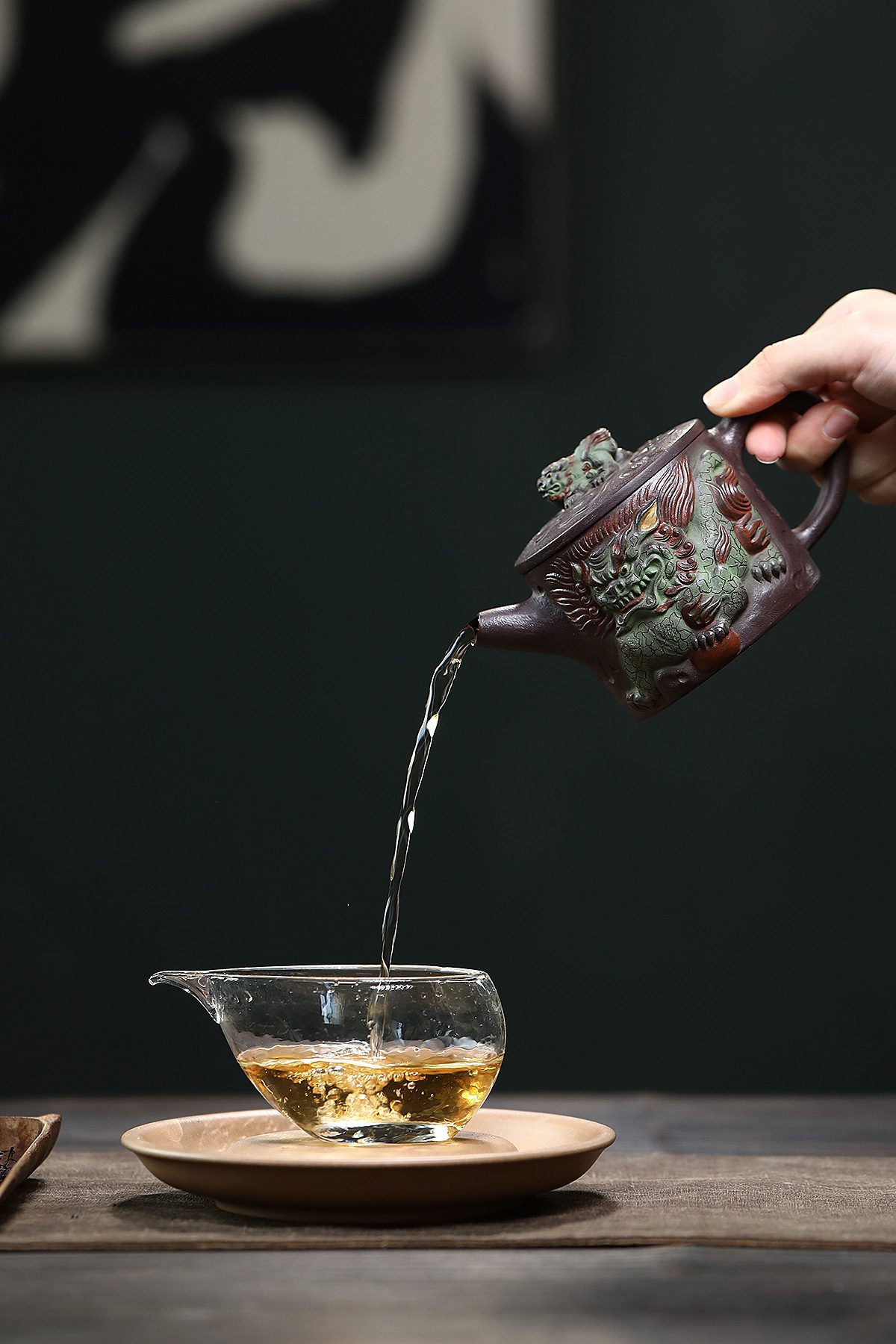 宜興紫砂壺原礦老紫泥麟趾呈祥漢瓦壺(280ml)，南山居手工紫砂壺，壺身浮雕祥瑞神獸紋飾，泥色古樸溫潤，正將金黃茶湯緩緩倒入晶瑩公道杯。
