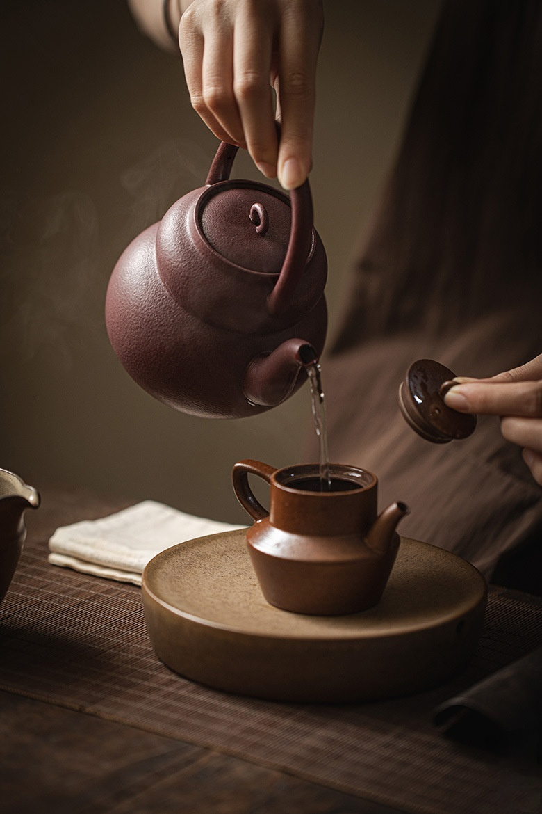 日式葫蘆提梁壺(570ml)，南山居精選紫砂茶壺沖泡茶湯，壺身砂質細膩，色澤溫潤，出水順暢，展現深厚茶道文化。