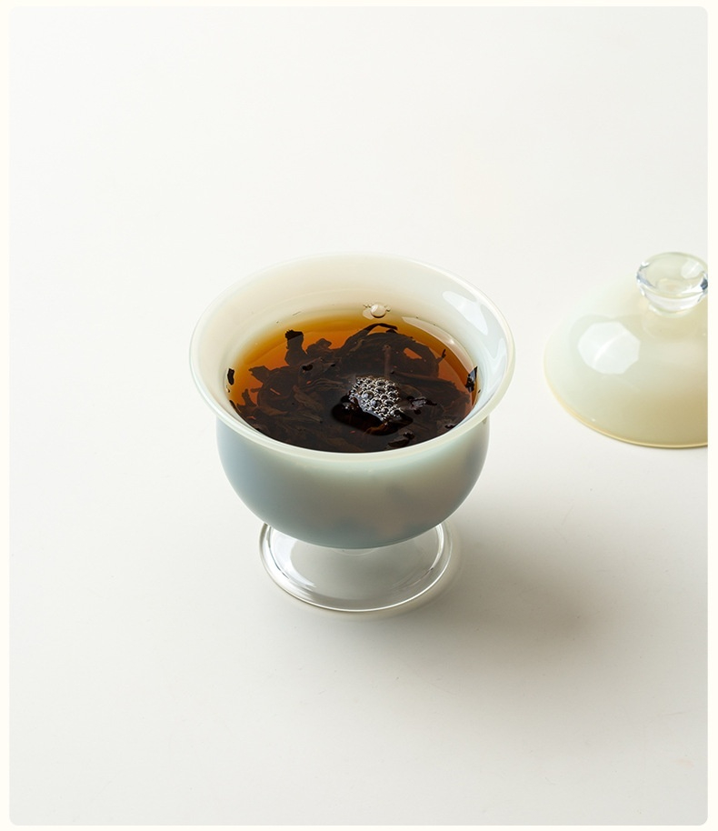 月光白高足蓋碗，南山居高雅手工陶瓷玻璃蓋杯，內盛烏龍茶葉，茶湯醇厚澄澈。