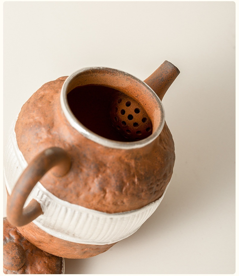 老岩泥鎏銀辰思壺，南山居手工粗獷陶壺，壺身仿岩石紋理，底部飾有白色條紋，壺口鑲嵌銀邊，展現獨特藝術風格。