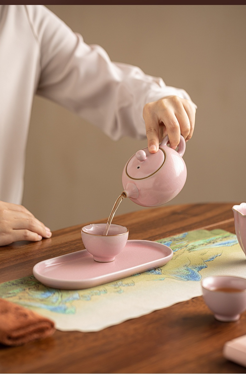 粉汝窯旅行茶具套組，南山居粉色開片釉陶瓷茶具套組，迷你茶壺正為同款茶杯注茶，展現溫潤優雅的手工茶具之美。