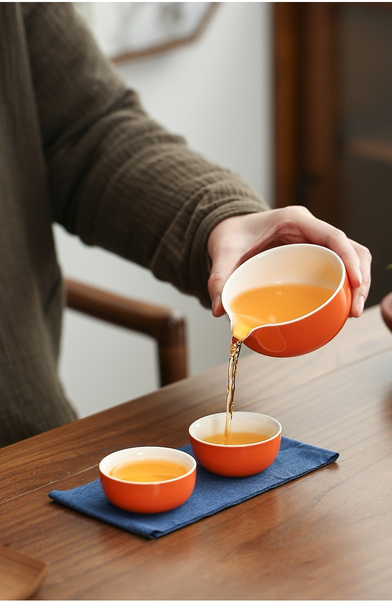 豬柿順遂快客杯，南山居橙白相間陶瓷公道杯，將金黃茶湯均勻注入圓潤茶杯，展現優雅品茗。