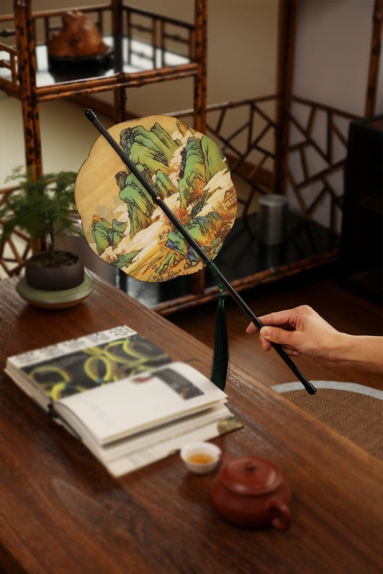 古畫竹絲腰扇，「南山居」茶席上的朱泥紫砂壺與雅緻茶杯，搭配手持古典山水團扇，營造品茗靜思的茶文化氛圍。